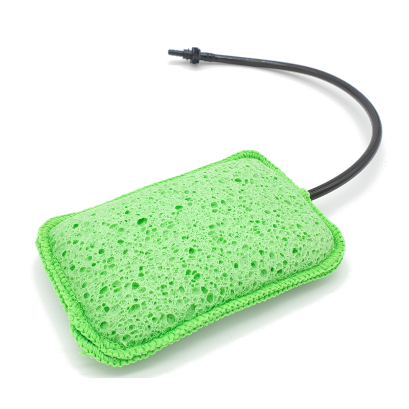 Image of Geyser Systems green scrub sponge attachment with porous texture and black hose connection, angled front view on white background.