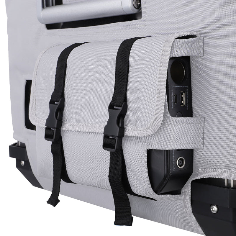 A close-up view of the side pocket on the ICECO APL55 portable refrigerator/freezer's light gray protective cover, featuring black adjustable straps and revealing various power ports, on a white background