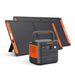 Image of Jackery Explorer 2000 portable power station with two foldable solar panels, black and orange design with carry handle, angled front view showing unit positioned in front of solar panels on a white background.