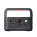Image of a Jackery Explorer 600 portable power station with integrated handle, black and gray body with orange accents and front control panel, straight-on front view on white background.