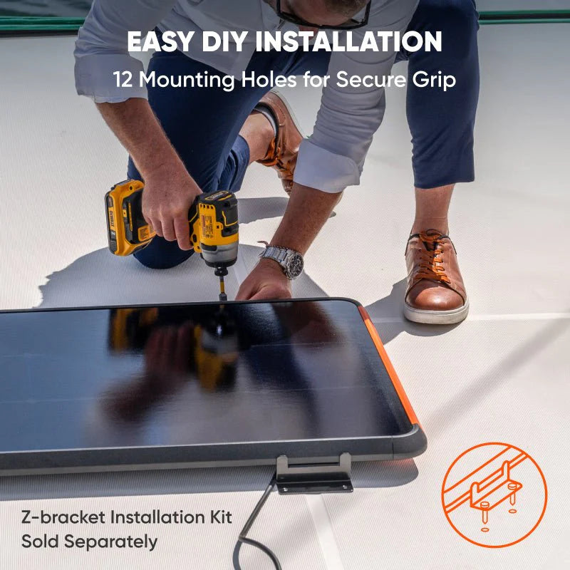 Image of Jackery SolarSaga 100 Prime solar panel being installed with a drill using mounting hardware, black panel with orange edge shown during DIY setup, angled top view in outdoor installation setting.
