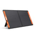 Image of Jackery SolarSaga 100W portable solar panel with black foldable design and orange side handles, panel propped on integrated stand, angled front and side view on white background.