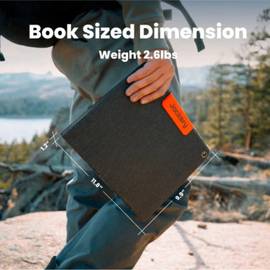Image of Jackery SolarSaga 40W Mini portable solar panel shown being carried outdoors, black foldable panel with orange logo and size measurements displayed, angled front view in outdoor nature setting.