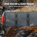Image of Jackery SolarSaga 40W Mini portable solar panel laid flat on rocky ground, black foldable panel with water droplets highlighting IP68 water and dust resistance, top-down angled view in outdoor setting.