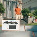 Image of a Jackery foldable portable solar panel system set up outdoors in front of a house, black photovoltaic panels with orange trim, front view with product layout inset showing folded and unfolded configurations.