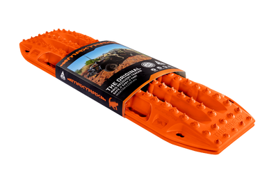 Image of an orange Maxtrax recovery board, wrapped with its product packaging displaying branding and an off-road vehicle, angled on a light gray background.