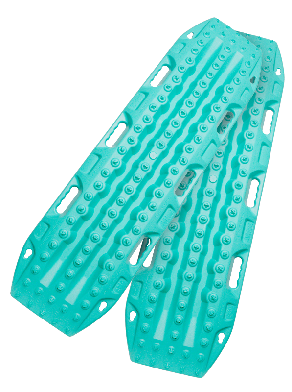 Image of teal off-road recovery traction boards with raised cleats and built-in handles, stacked in an angled front and side view on black background.