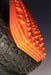 Close-up image of stacked orange MAXTRAX MKII recovery tracks mounted to a spare tire, viewed from a low angle against a dark sky.