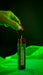 Image of MK Outdoor premium butane lighter refill 20ml with red cap removed, green canister upright with nozzle exposed, close-up front view against dark green background.
