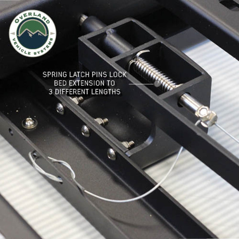 Image of Overland Vehicle Systems truck bed extension close-up showing spring latch pins locking the extension to three different lengths, with text overlay highlighting the feature