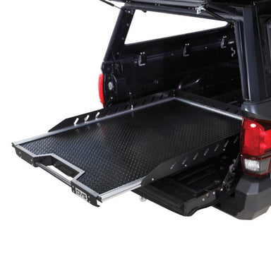 Image of Overland Vehicle Systems truck bed extension with a diamond plate surface, extended out of the truck bed, side view with visible mounting rails and handle for easy pull-out