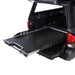 Image of Overland Vehicle Systems truck bed extension with a diamond plate surface, extended out of the truck bed, side view with visible mounting rails and handle for easy pull-out