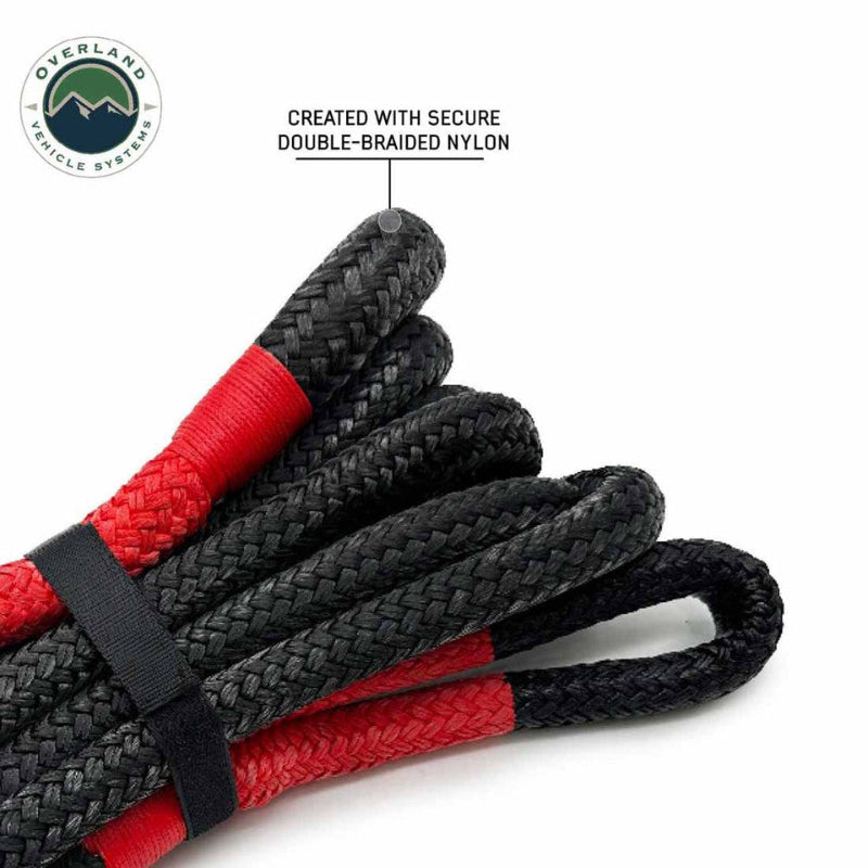 Image of Overland Vehicle Systems kinetic recovery rope showing double-braided nylon construction with black braided rope and red reinforced loops, coiled and secured with strap, angled view on white background.