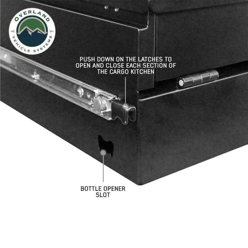 Image of a close-up on the side of a black Overland Vehicle Systems (OVS) Cargo Box, showing a drawer latch and a "BOTTLE OPENER SLOT," with text indicating to "PUSH DOWN ON THE LATCHES TO OPEN AND CLOSE EACH SECTION OF THE CARGO KITCHEN," all on a white background