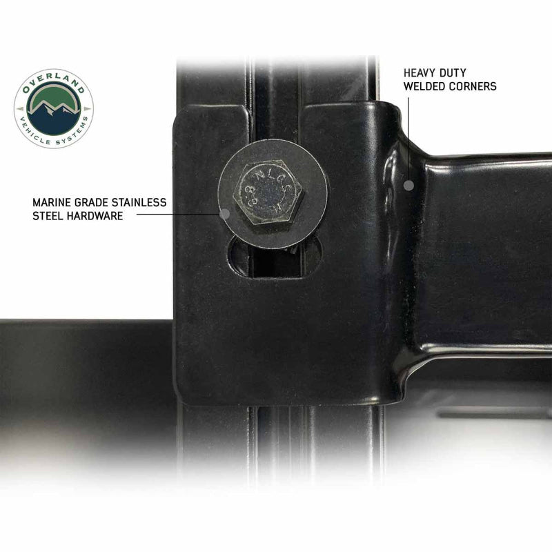 Image of a close-up of a black truck bed rack, highlighting marine-grade stainless steel hardware and heavy-duty welded corners. The focus is on a hex bolt and the solid construction, with product labels indicating durability features, viewed on a white background
