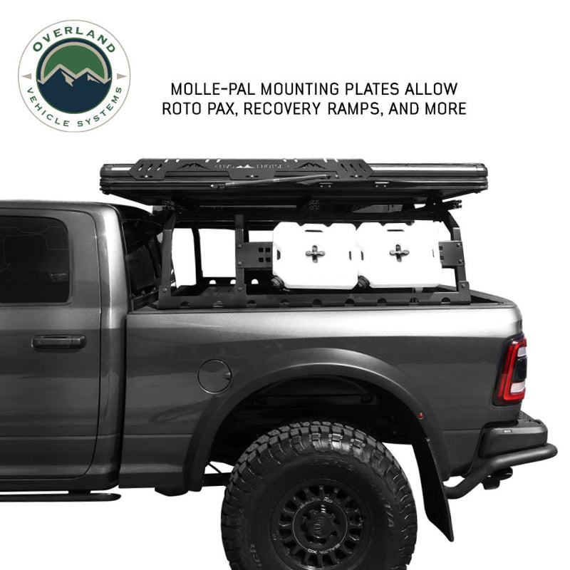 Image of Overland Vehicle Systems roof rack mounted on a truck with MOLLE-PAL mounting plates holding Roto Pax fuel cans and recovery ramps, side view with a text overlay highlighting the mounting plate features