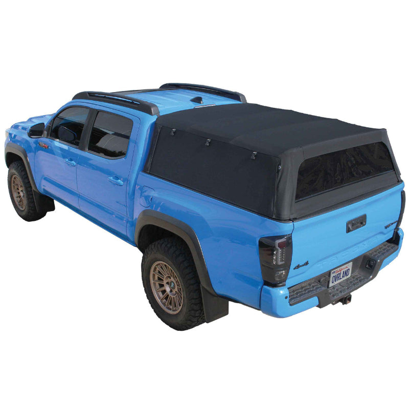 Image of a blue pickup truck with a black soft shell camper top, angled rear and side view on a white background. The soft shell is made of canvas with an aluminum frame