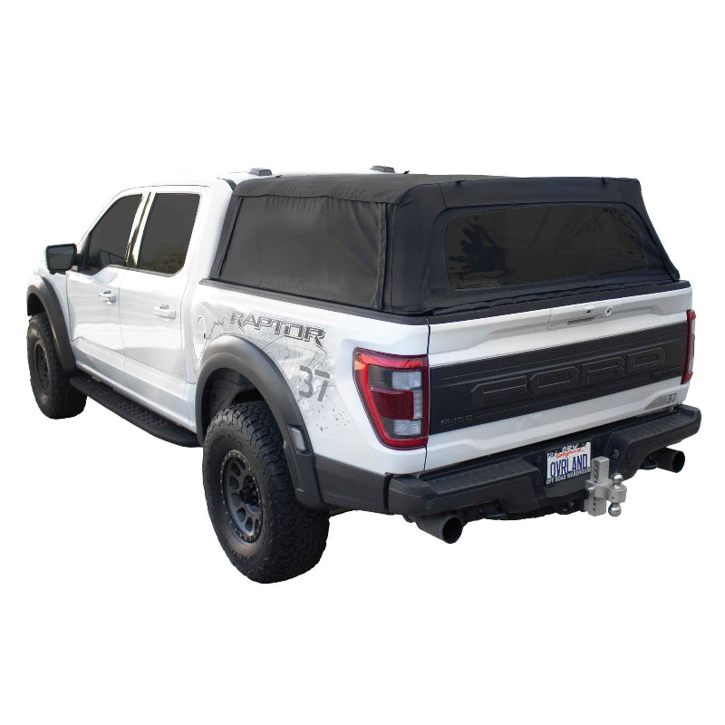 Image of a white Ford Raptor pickup truck with a black soft shell camper top, angled rear and side view on a white background. The soft top is made of a durable black canvas with an aluminum frame