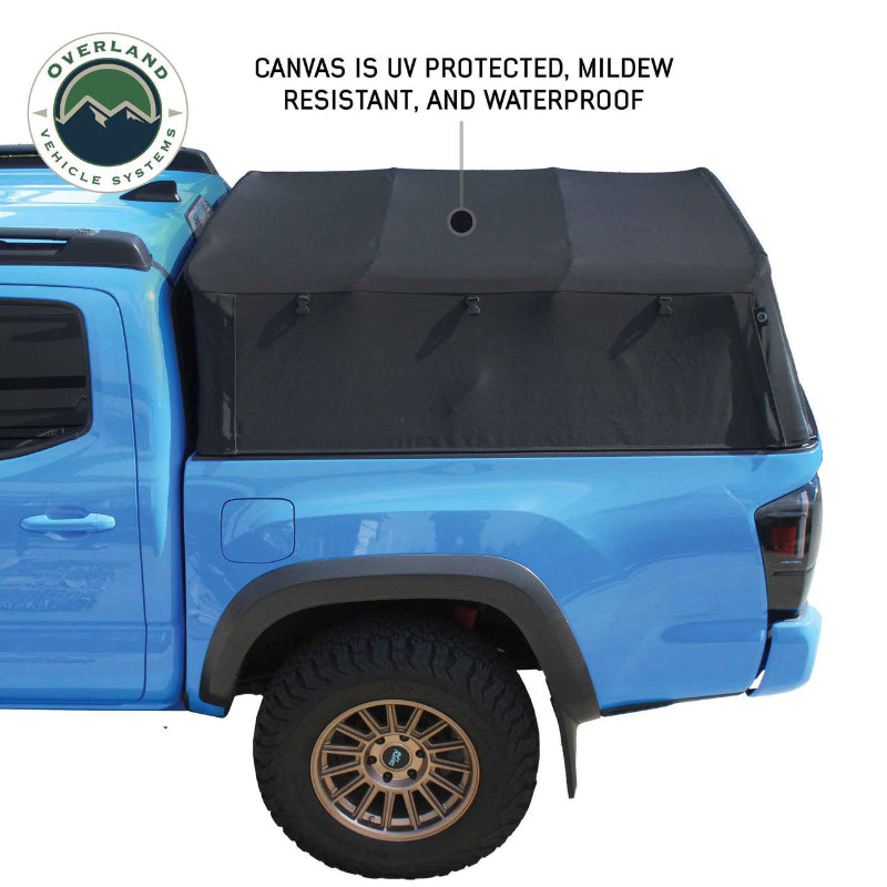 Image of a black soft shell camper top on a blue pickup truck, side view on a white background. Text reads "CANVAS IS UV PROTECTED, MILDEW RESISTANT, AND WATERPROOF" with a pointer to the top's fabric