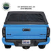 Image of an Overlanding Vehicle Systems Explorer Soft Shell bed topper on a blue Toyota Tacoma pickup truck, angled rear view. The soft shell topper is made of black diamond canvas and has a clear vinyl rear window