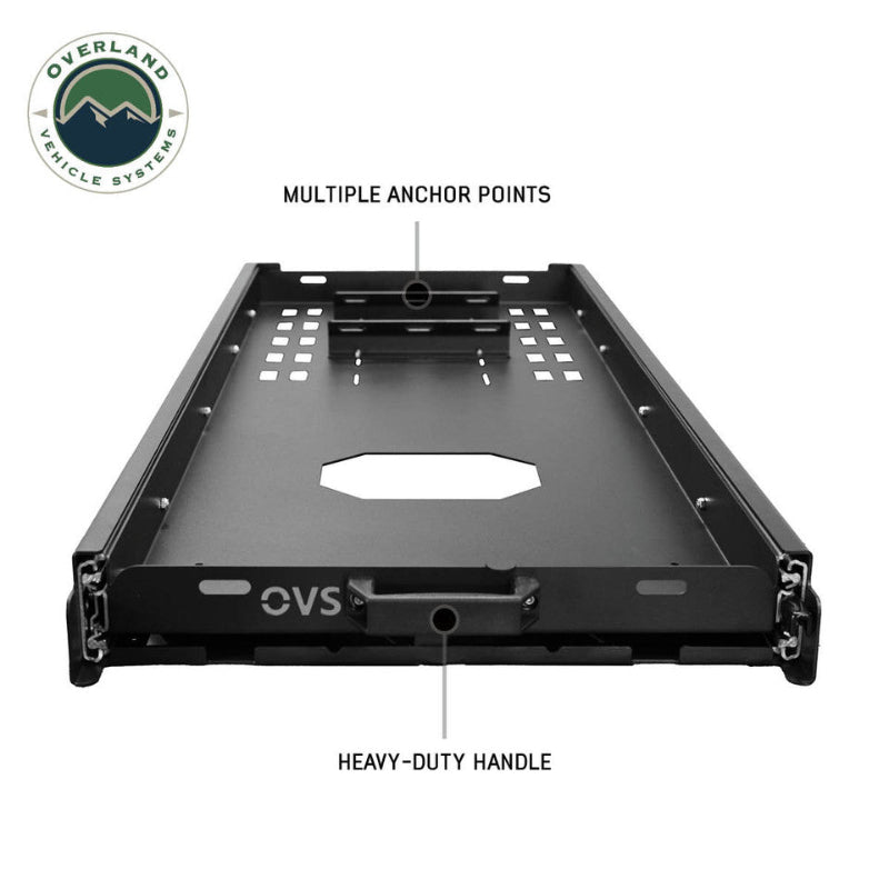Image of an OVS black steel refrigerator slide from a front-facing, slightly elevated view, highlighting its "MULTIPLE ANCHOR POINTS" and "HEAVY-DUTY HANDLE" with text labels. This emphasizes the slide's robust construction and secure design features for overlanding gear