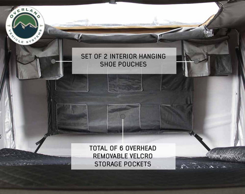 An image showing the interior of the Bushveld Hard Shell Roof Top Tent, highlighting a "SET OF 2 INTERIOR HANGING SHOE POUCHES" and a "TOTAL OF 6 OVERHEAD REMOVABLE VELCRO STORAGE POCKETS" against the light grey interior fabric