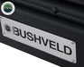 An image of a close-up, angled view of a silver "BUSHVELD" brand plate attached to a black textured surface