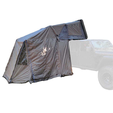 Image of an OVS Overland Vehicle Systems Bushveld tent fully deployed, showcasing a side room extension. The tent is mounted on top of an off-road vehicle, and the entire setup is shown against a white background