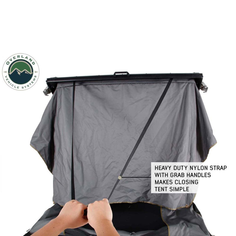 Image of Mamba 3 Clam Shell Roof Top Tent showing a heavy-duty nylon strap with grab handles for easy closing, with hands pulling the strap, close-up view on a white background