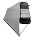 Image of an overhead view of the Overland Vehicle Systems' Nomadic 180 Awning fully deployed from a truck. The awning is light gray and extends from the passenger side and rear of the vehicle, providing a wide-angle shade
