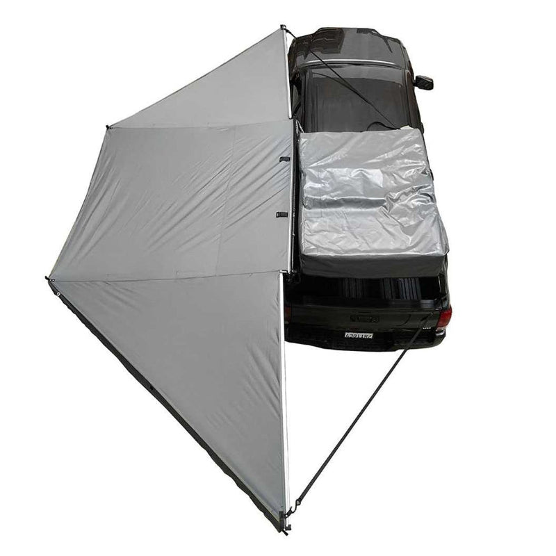 Image of an overhead view of the Overland Vehicle Systems' Nomadic 180 Awning fully deployed from a truck. The awning is light gray and extends from the passenger side and rear of the vehicle, providing a wide-angle shade