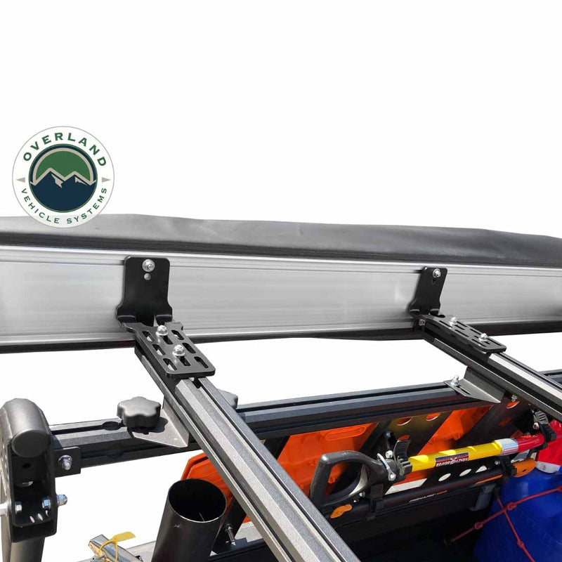 Image of the OVS Nomadic Awning mounted to a vehicle's roof rack, showing a close-up of the heavy-duty mounting brackets and hardware