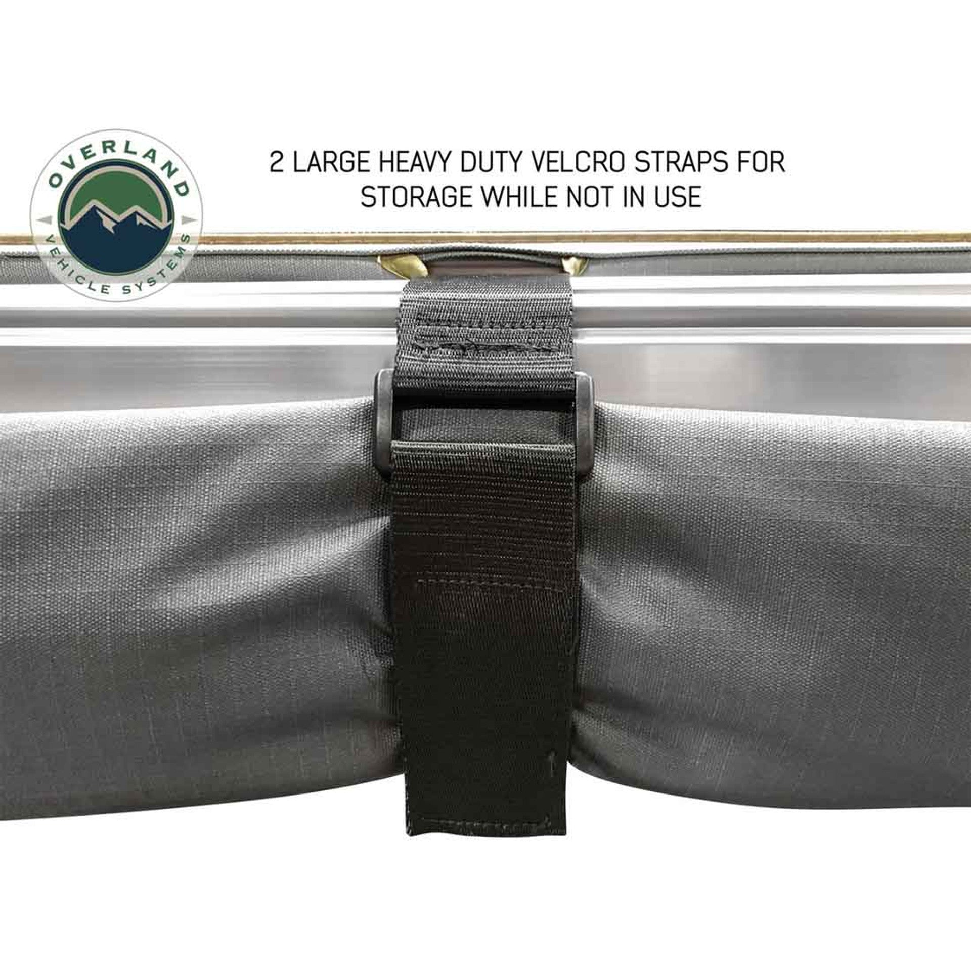 Image of the OVS Nomadic Awning rolled up and secured with a large heavy-duty Velcro strap for storage. The awning fabric is a dark grey color