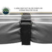 Image of a close-up of a heavy-duty black Velcro strap and buckle holding the grey fabric of an Overland Vehicle Systems 270-degree awning securely against the aluminum casing. The text highlights that these are used for storage when the awning is not in use