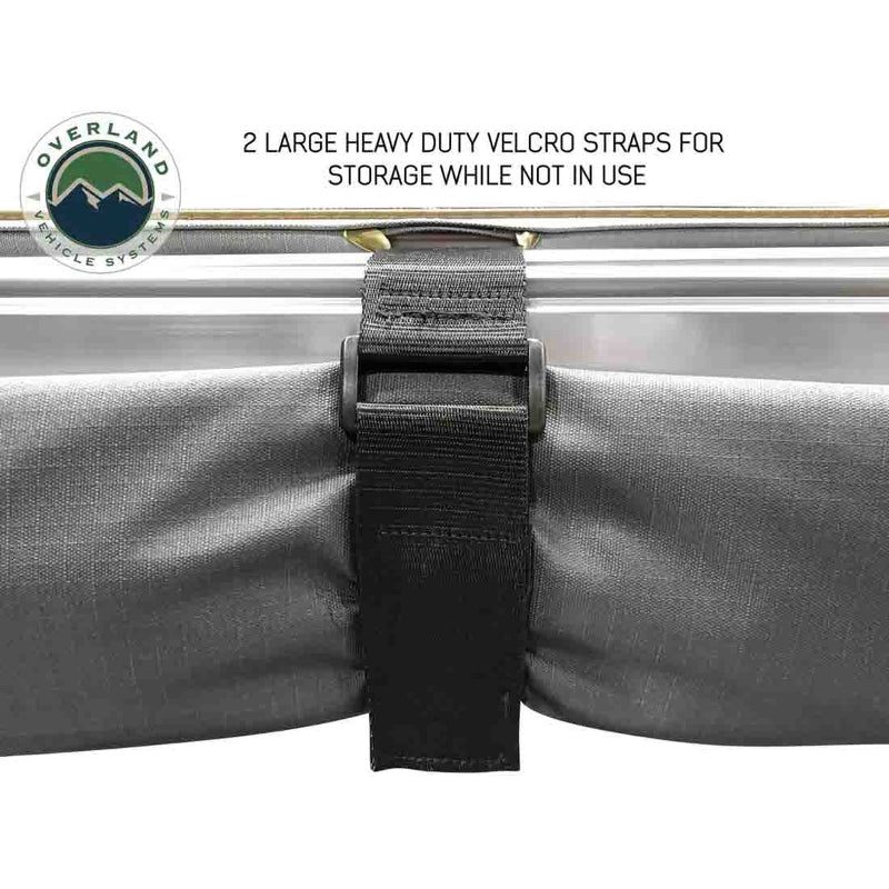 Image of a close-up of a heavy-duty black Velcro strap and buckle holding the grey fabric of an Overland Vehicle Systems 270-degree awning securely against the aluminum casing. The text highlights that these are used for storage when the awning is not in use