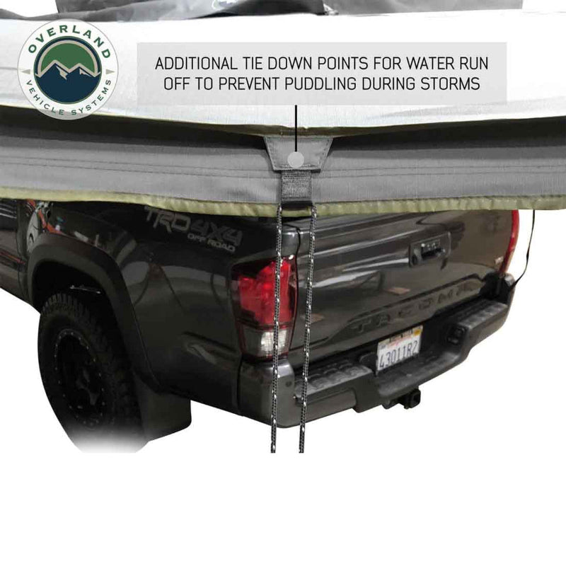 Image of a tie-down point on a grey Overland Vehicle Systems awning, attached to a grey pickup truck. The tie-down is designed for water runoff to prevent puddling during storms
