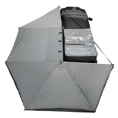 Image of an Overland Vehicle Systems 270-degree awning with walls, fully deployed from the side of a vehicle. The awning has grey fabric with a black underside and is shown from a high-angle view on a white background