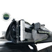 Image of a close-up of the heavy-duty aluminum hinge and hardware of an Overland Vehicle Systems 270-degree awning. The awning is partially unzipped from its black travel cover and mounted to a vehicle's rooftop, with the green awning fabric visible