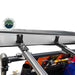 Image of the side view of an Overland Vehicle Systems 270-degree awning in its black travel cover, attached to a roof rack with two black mounting brackets. The aluminum awning casing is visible, as well as a yellow shovel and other gear mounted to the roof rack