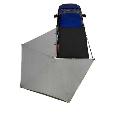 Image of OVS HD Nomadic 270 LT Awning partially deployed, light gray fabric, driver-side mounted on a blue vehicle with black roof rack, top-down view on white background