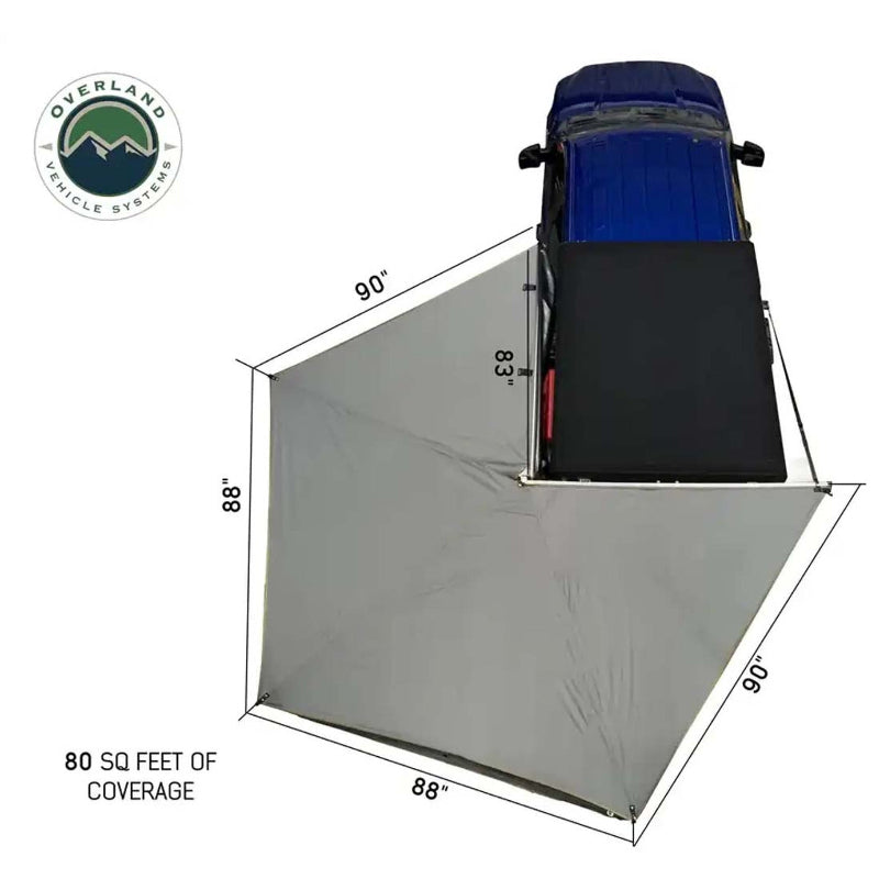 Image of a gray vehicle awning packed in its black 1000G PVC travel bag with heavy-duty zippers, mounted on the roof rack of a blue Ford F-150 truck. The travel cover dimensions are displayed as 83" x 7" x 5"