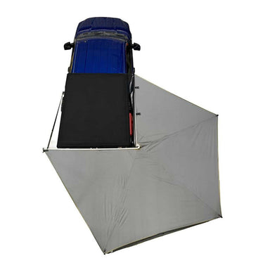 Image of a blue pickup truck with a Peregrine Awning partially deployed. The grey awning is extended from the side and rear of the vehicle, creating a shaded area. The view is from directly above on a white background