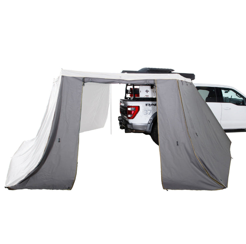 Image of a white truck with a Peregrine Awning and a full set of zippered walls creating an enclosed space. The grey fabric walls with green trim are shown fully deployed from the main awning structure, angled side view on a white background