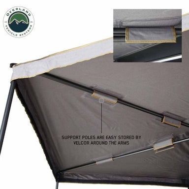 Image of a roof-mounted awning underside showing gray fabric canopy with support poles neatly stored using Velcro straps along the arms, angled underside detail view on white background.
