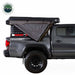 Image of a pickup truck with a roof-mounted 270-degree awning partially deployed, showing gray fabric folded outward from the side over the truck bed, side profile view on white background.