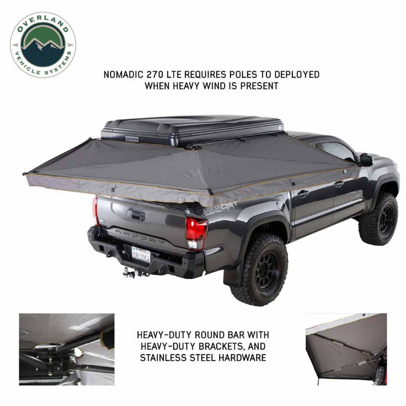 Image of a pickup truck with a roof-mounted 270-degree awning fully deployed, gray fabric canopy extending around the rear and side with reinforced hardware details, angled rear and side view on white background.