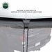 Image of a roof-mounted awning detail showing gray fabric edge with additional tie-down point and cord for water runoff control, close-up exterior view on white background.