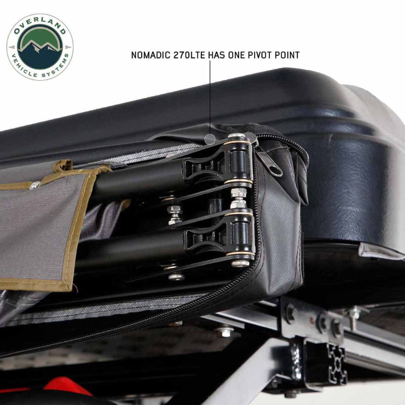 Image of a roof-mounted awning pivot mechanism showing aluminum support arms, reinforced hinge point, and stainless steel hardware inside the protective cover, close-up detail view on white background.