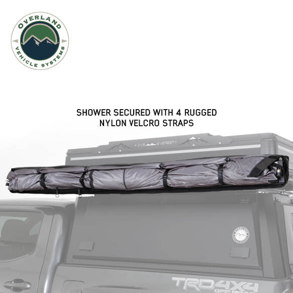 Image of an OVS HD Nomadic 2-person car-side shower and privacy room fully packed on a roof rack and secured with rugged nylon Velcro straps, shown in side view on a white background.