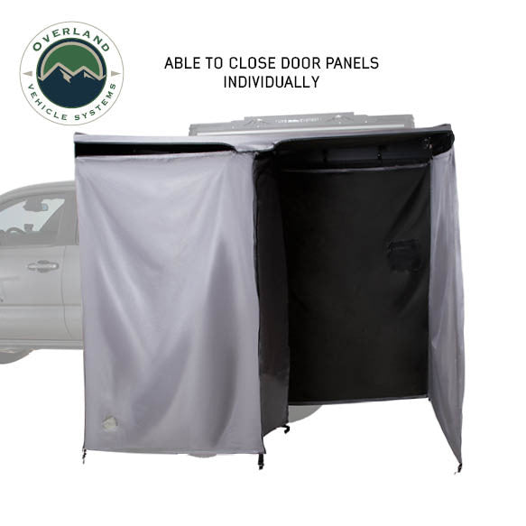 Image of an OVS HD Nomadic 2-person car-side shower and privacy room showing individually closable door panels with grey and black fabric sections, displayed in angled front and side view on a white background.